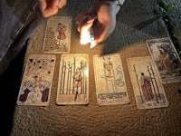 a person lighting a candle next to a group of tarot cards